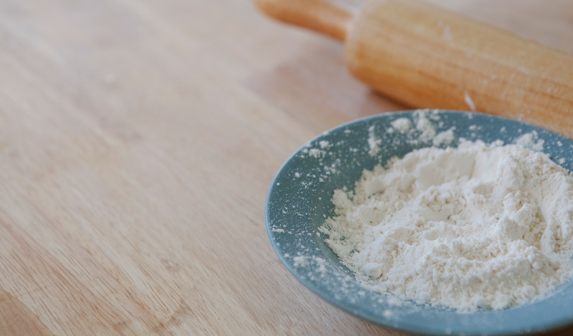 A bowl of baking soda beside a rolling pin