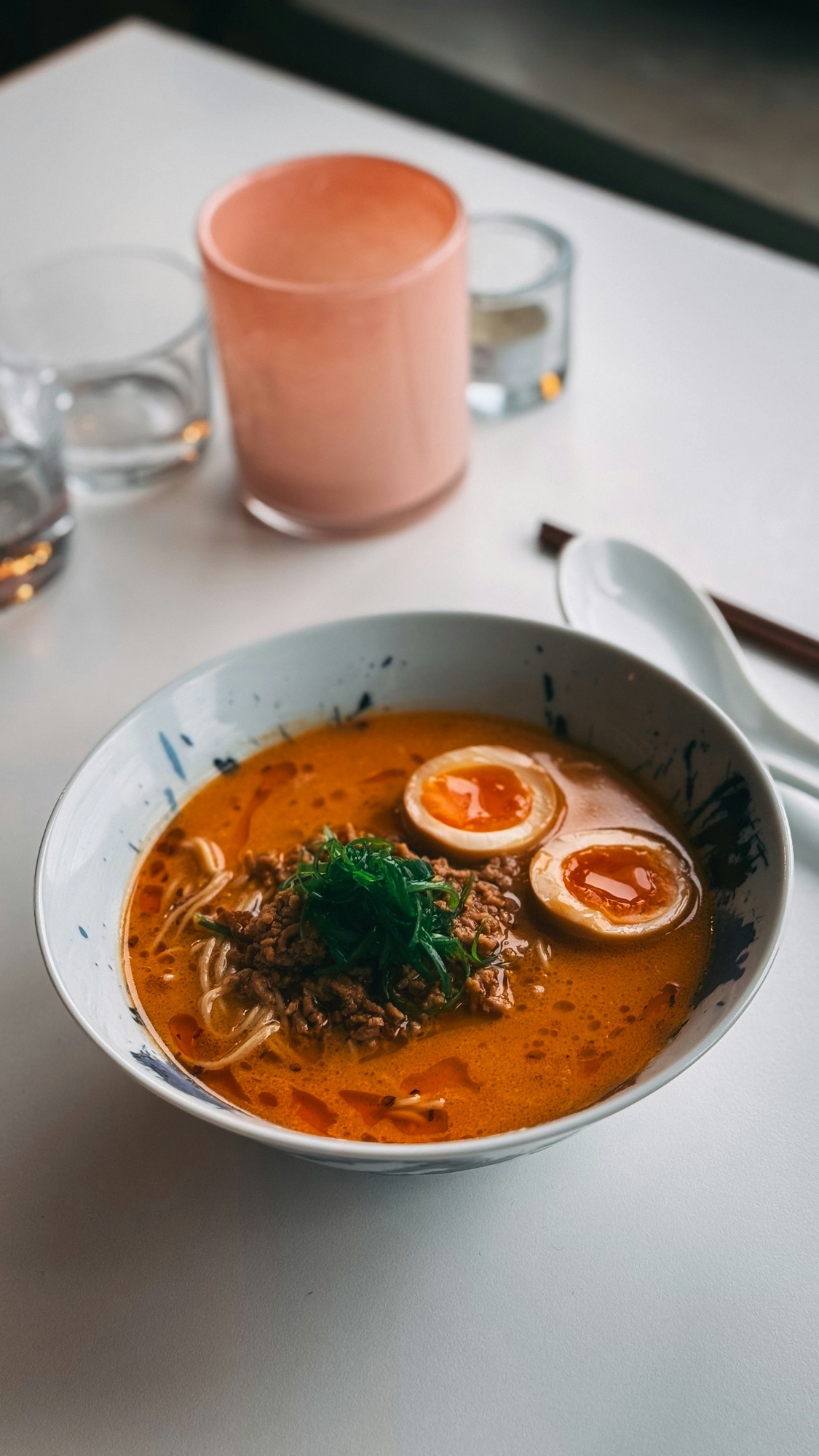 A bowl of umami-rich ramen with soft-boiled eggs, ground meat, and scallions